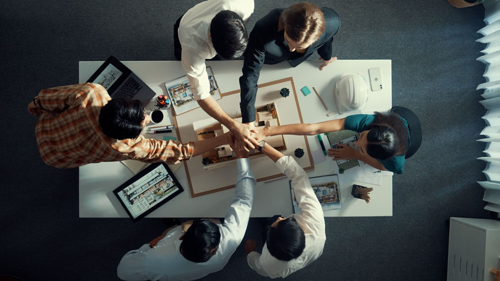 Aerial view of office workers putting their hands in for a group hand shake